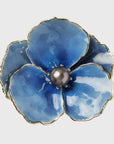 A blue enamel flower napkin ring with a gold border and a pearl center.