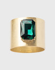 A gold-colored napkin ring featuring a large emerald-cut green gemstone.