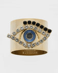 A gold-colored napkin ring featuring an evil eye design with blue and black accents.