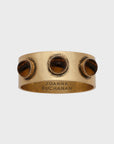 A set of brass napkin rings with a tiger's eye stone, featuring an antique gold finish.