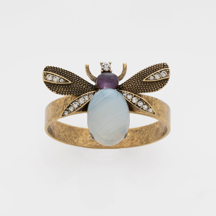 A napkin ring featuring a winged bug design with antique gold finish and a semi-precious agate stone body.