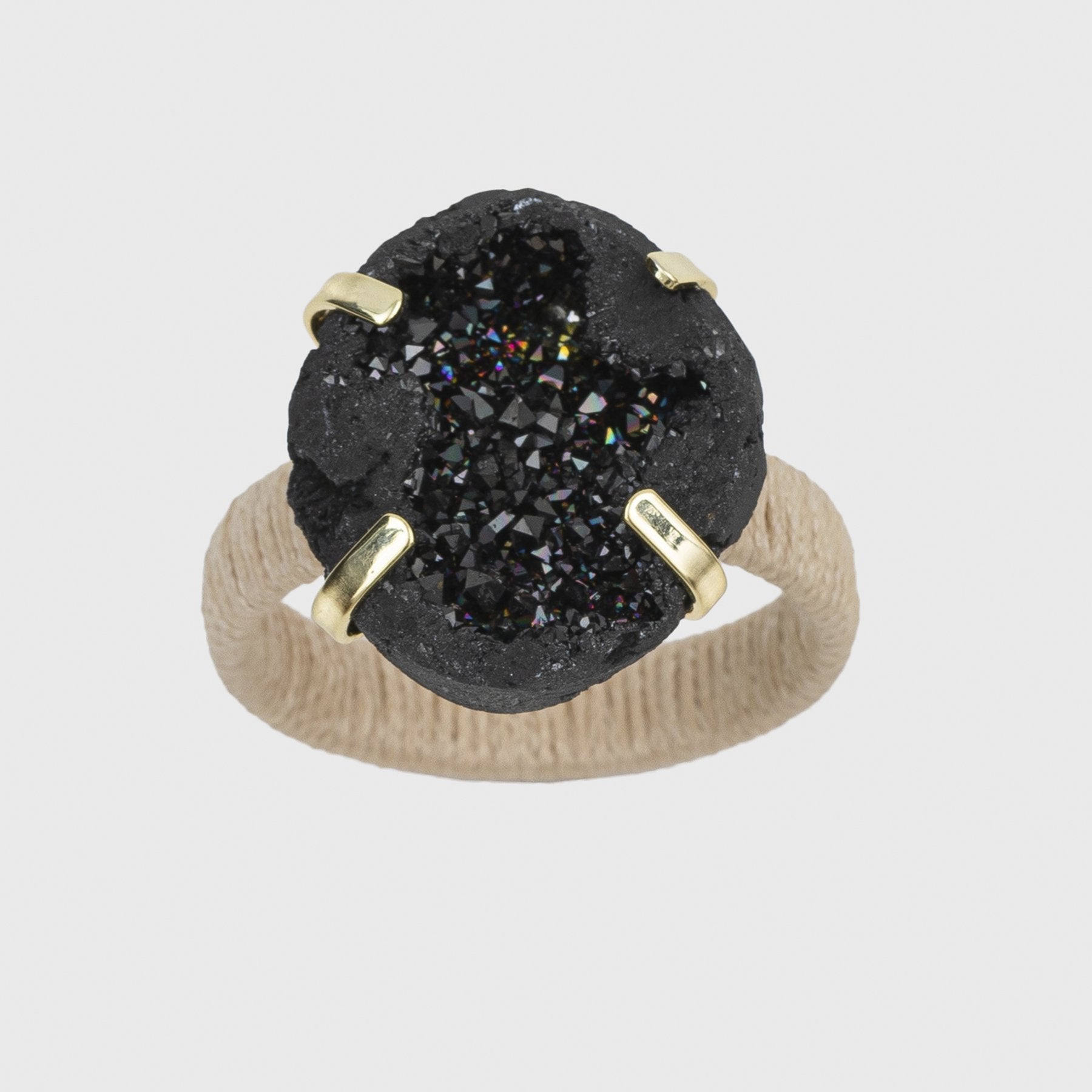 A napkin ring featuring a black druzy stone with a natural wrapped raffia band and gold-colored accents.