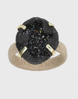 A napkin ring featuring a black druzy stone with a natural wrapped raffia band and gold-colored accents.