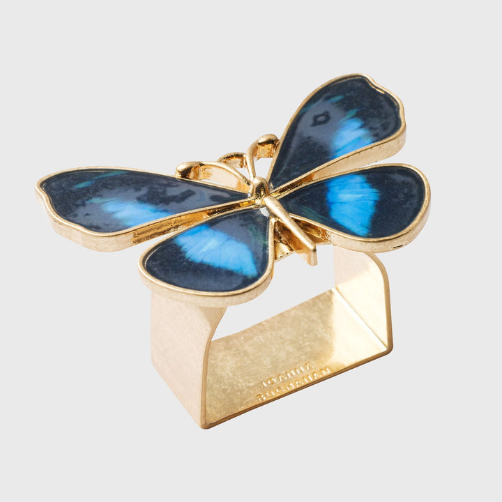 A gold-colored napkin ring featuring a blue butterfly design on top.