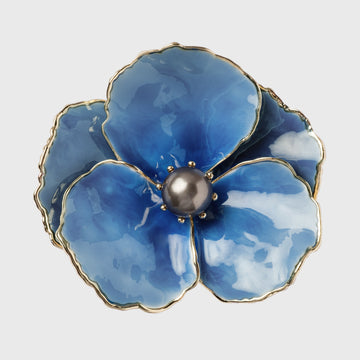 A blue enamel flower napkin ring with a gold border and a pearl center.