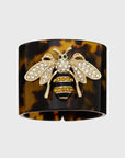 A tortoiseshell resin napkin ring with a stripey bee design in the center.