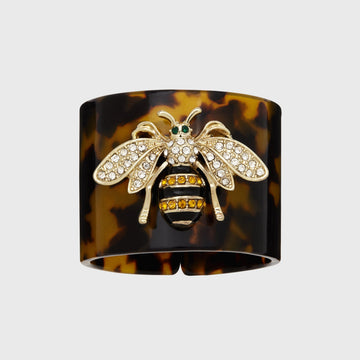 A tortoiseshell resin napkin ring with a stripey bee design in the center.