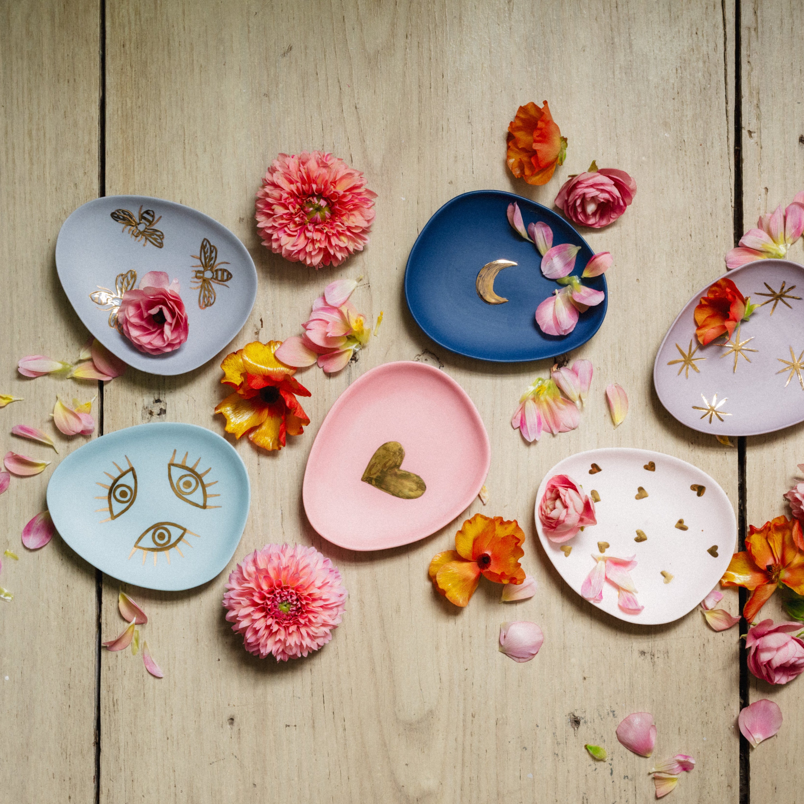 Decorative plates with floral and geometric designs on a wooden surface with flowers.