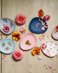 Decorative plates with floral and geometric designs on a wooden surface with flowers.