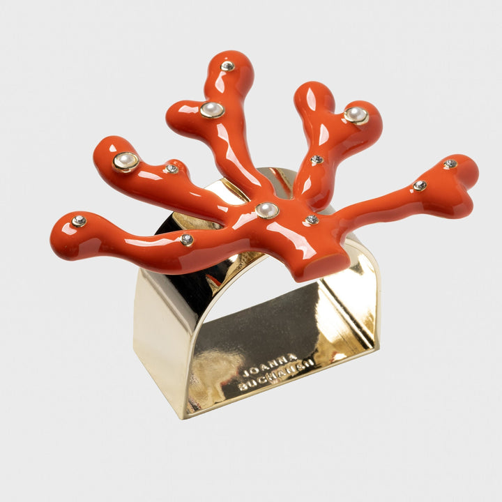 A set of coral-colored napkin rings with an intricate design
