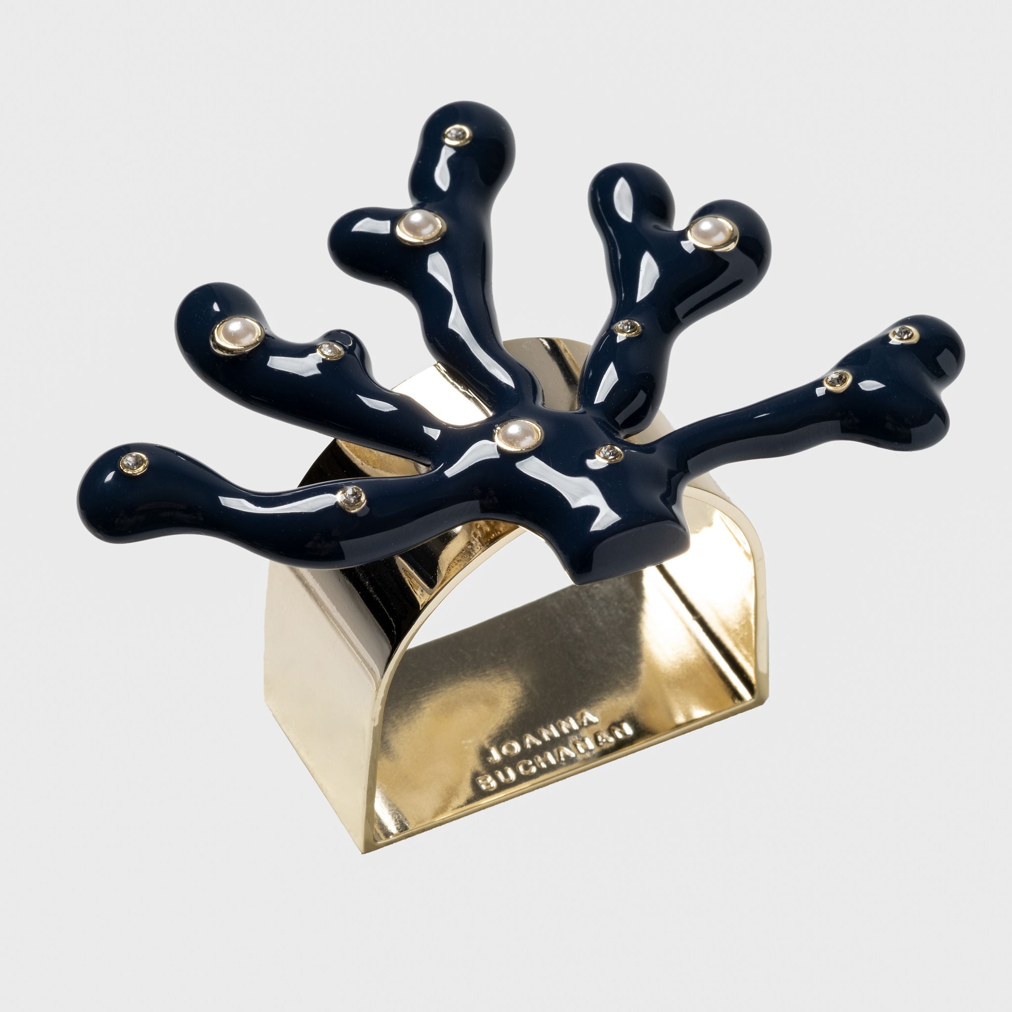 A navy blue coral-shaped napkin ring with gold detailing and hand-set stones.