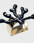 A navy blue coral-shaped napkin ring with gold detailing and hand-set stones.