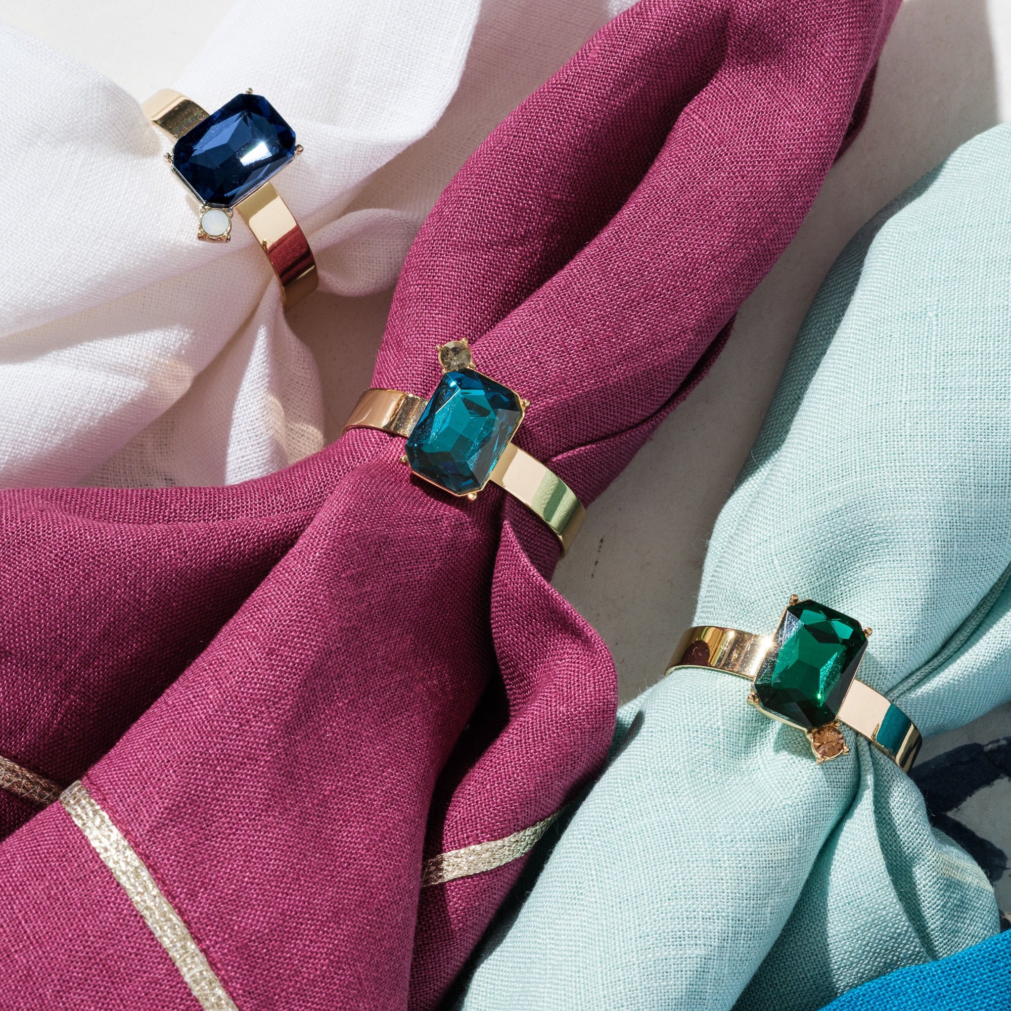Napkin rings with gemstone-like ends on pink and blue napkins.