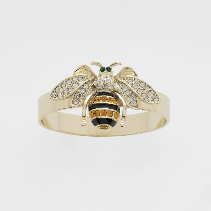 A gold-colored napkin ring featuring a skinny stripey bee design with black, white, and orange details.