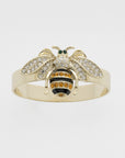 A gold-colored napkin ring featuring a skinny stripey bee design with black, white, and orange details.