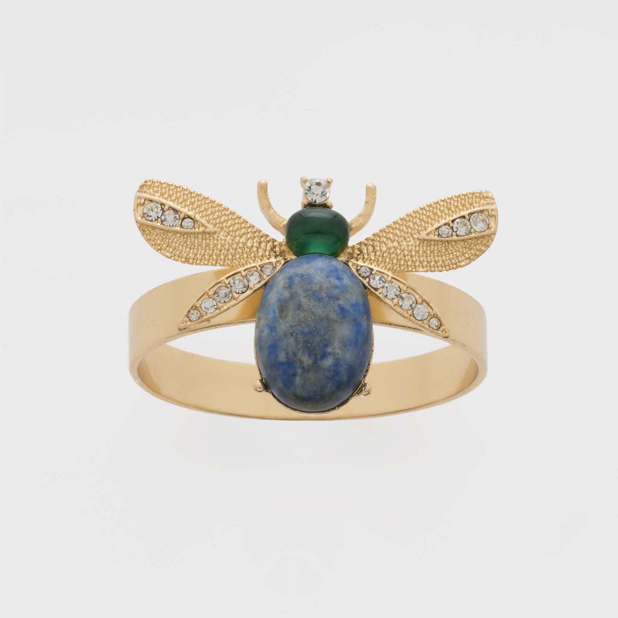 A gold-colored napkin ring featuring a lapis lazuli stone and intricate wing details, designed to resemble a bug.