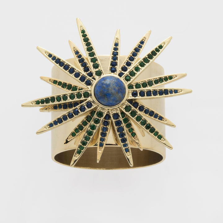 A gold-colored starburst napkin ring featuring a central lapis lazuli stone with blue and green gemstone accents.