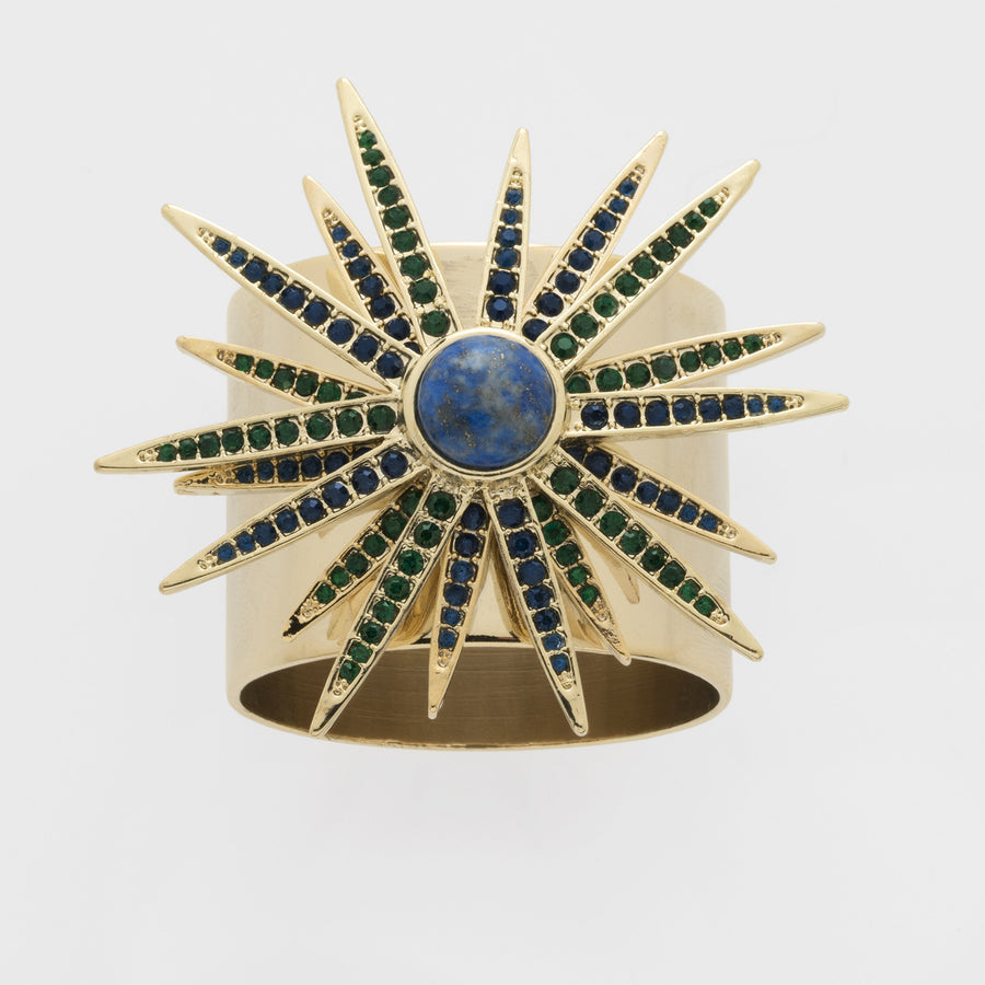 A gold-colored starburst napkin ring featuring a central lapis lazuli stone with blue and green gemstone accents.
