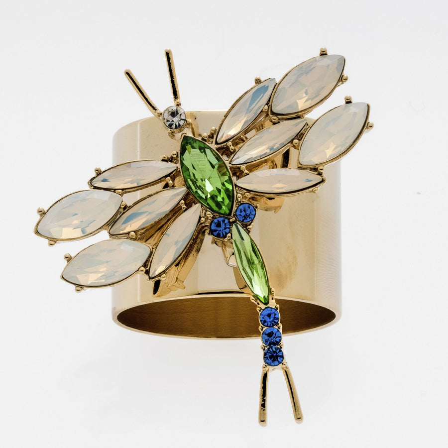 A gold-colored napkin ring featuring a dragonfly design with green and blue accents, and opal colored glass stones.