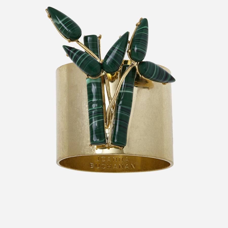 A gold-colored bamboo napkin ring with a jungle green leaf pattern on top.