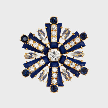A navy and crystal brooch shaped like a starburst with a central large crystal, surrounded by smaller crystal accents and navy blue enamel.