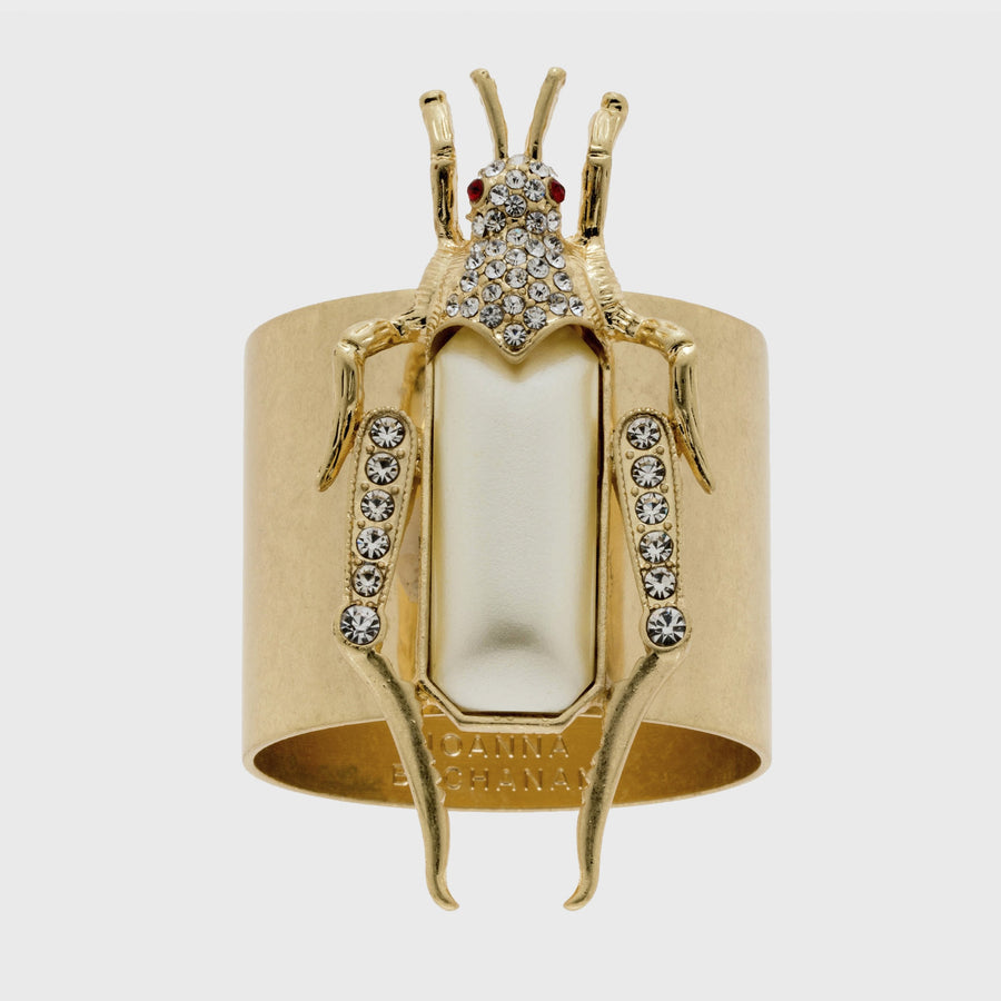 A gold-colored napkin ring featuring a pearl-like grasshopper motif with detailed legs and antennae