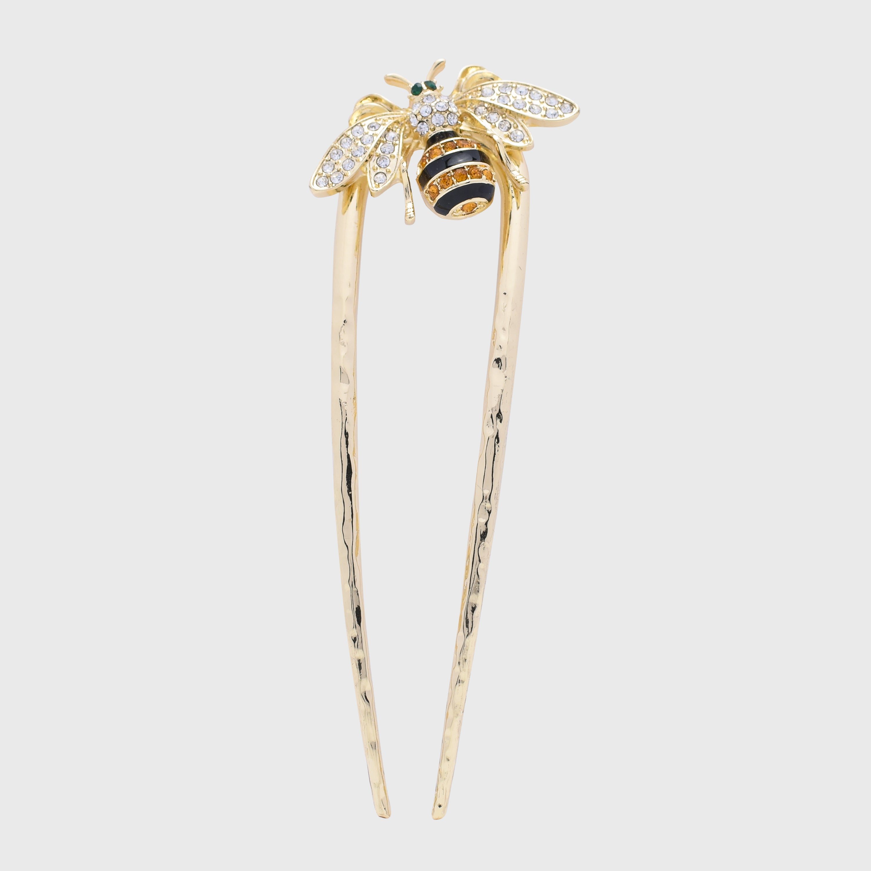 Gold hairpin with bee design on a light gray background