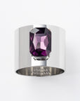 A silver napkin ring with a large amethyst gemstone set in the center, on a white background.