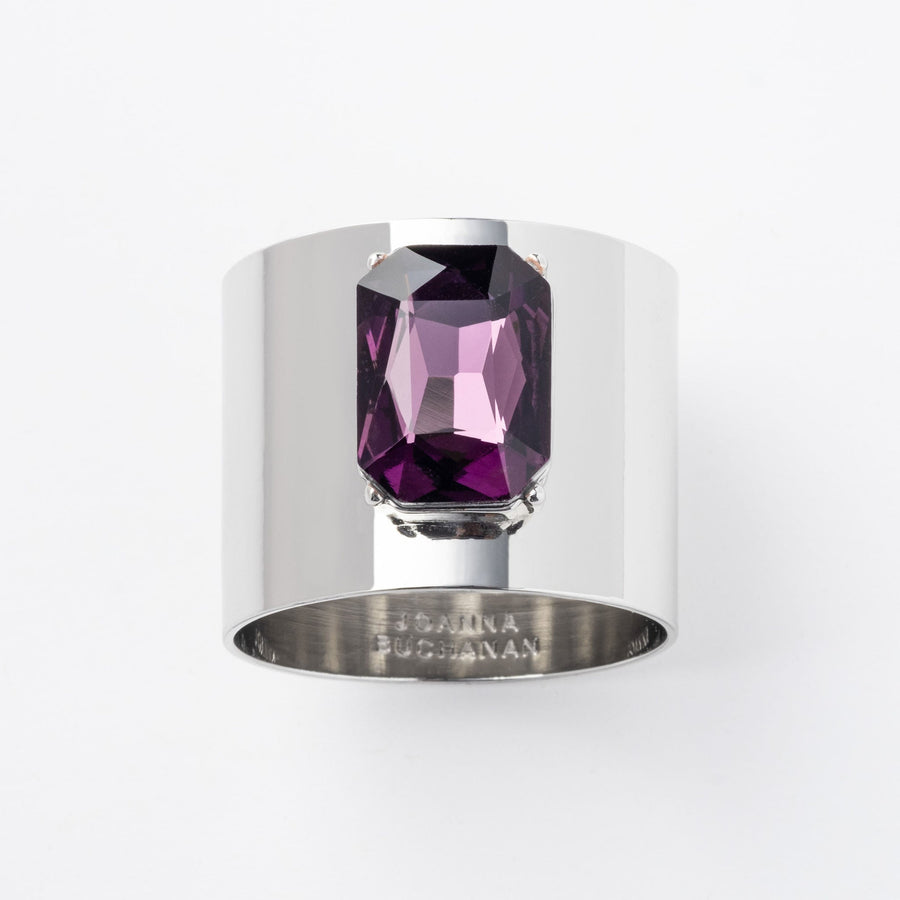 A silver napkin ring with a large amethyst gemstone set in the center, on a white background.