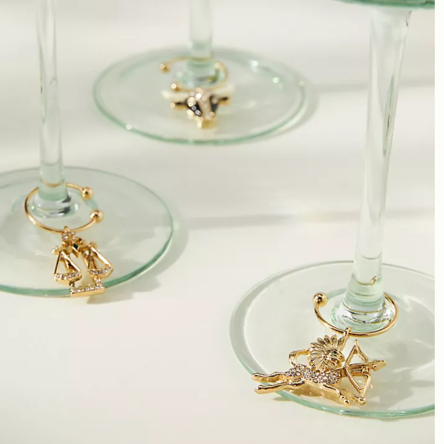 Gold wine glass charms with decorative elements on a white surface