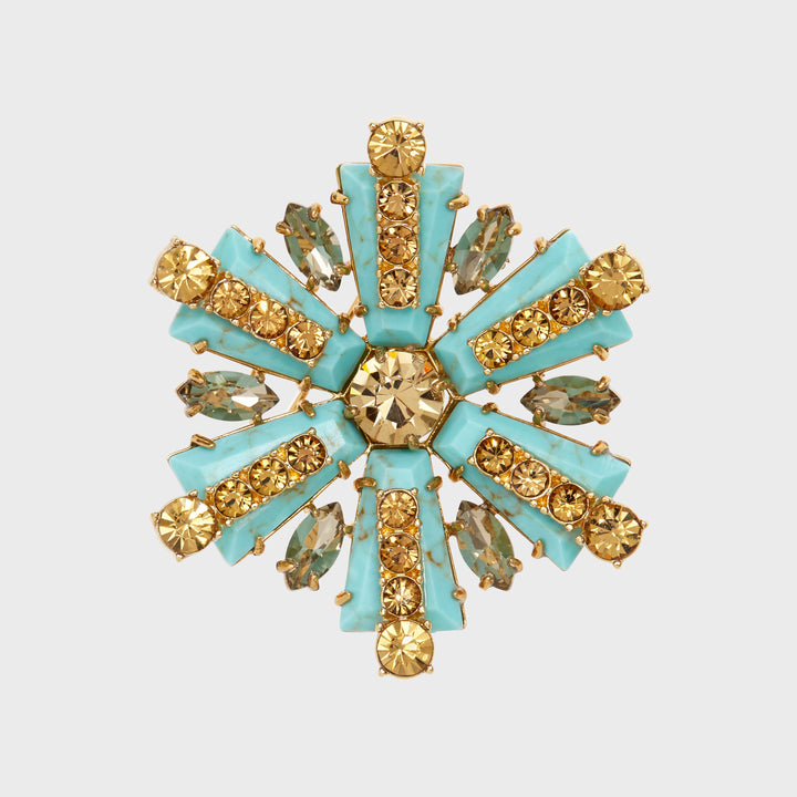 A star-shaped brooch with turquoise and gold-colored stones