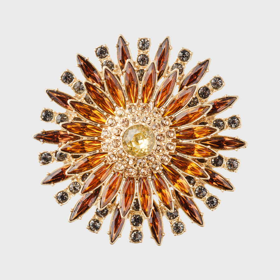 A set of four ornate napkin rings with amber-colored gemstones and gold-toned metal.