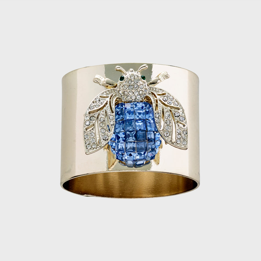 A gold-colored napkin ring featuring a blue sparkle bee design.