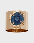A gold-colored napkin ring featuring a crystal quartz with a blue center