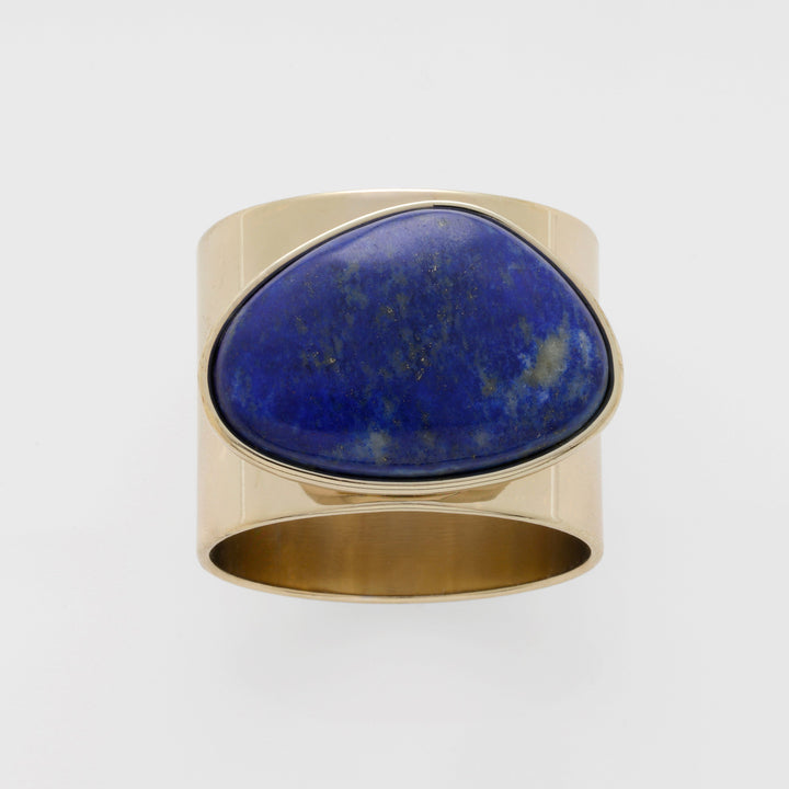 A gold-colored napkin ring with a lapis lazuli stone set in the center,