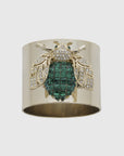 A gold-colored napkin ring featuring an emerald green bee design with sparkling embellishments.