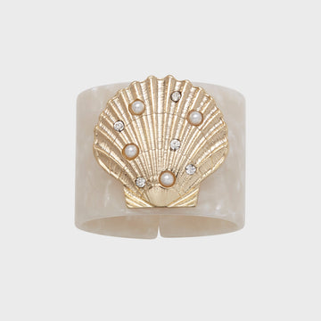 A white resin napkin ring with a gold-colored shell design and pearl-like embellishments.