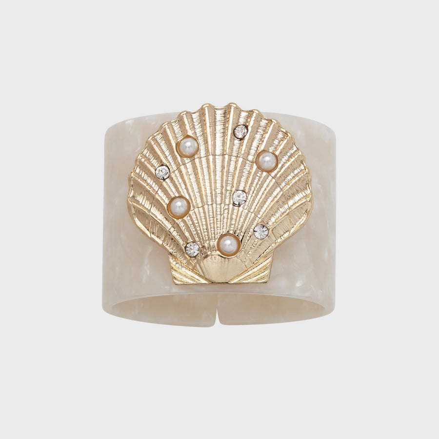 A white resin napkin ring with a gold-colored shell design and pearl-like embellishments.