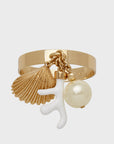 A gold-colored napkin ring featuring dangling coral and shell charms with a pearl-like element.