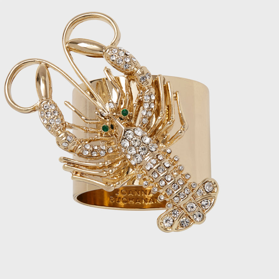 A gold-colored napkin ring featuring a crystal-encrusted lobster design with green accents for eyes.