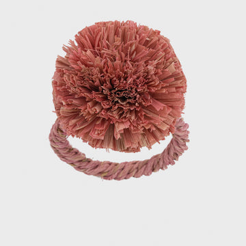 A pink straw pompom napkin ring.