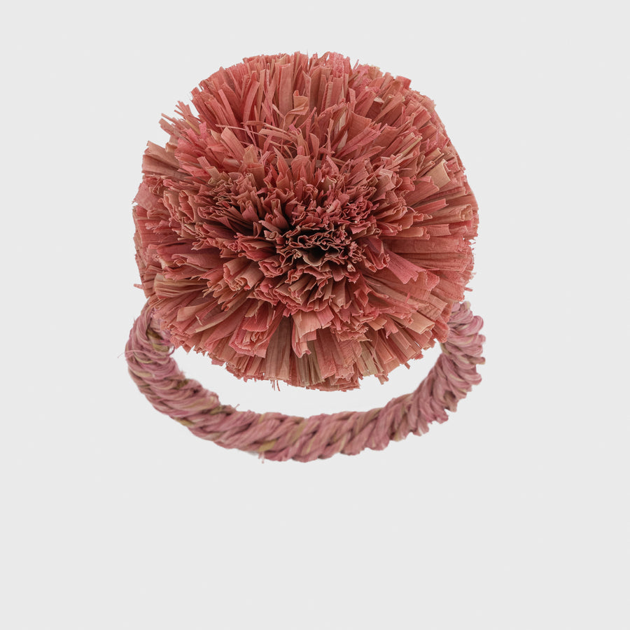 A pink straw pompom napkin ring.