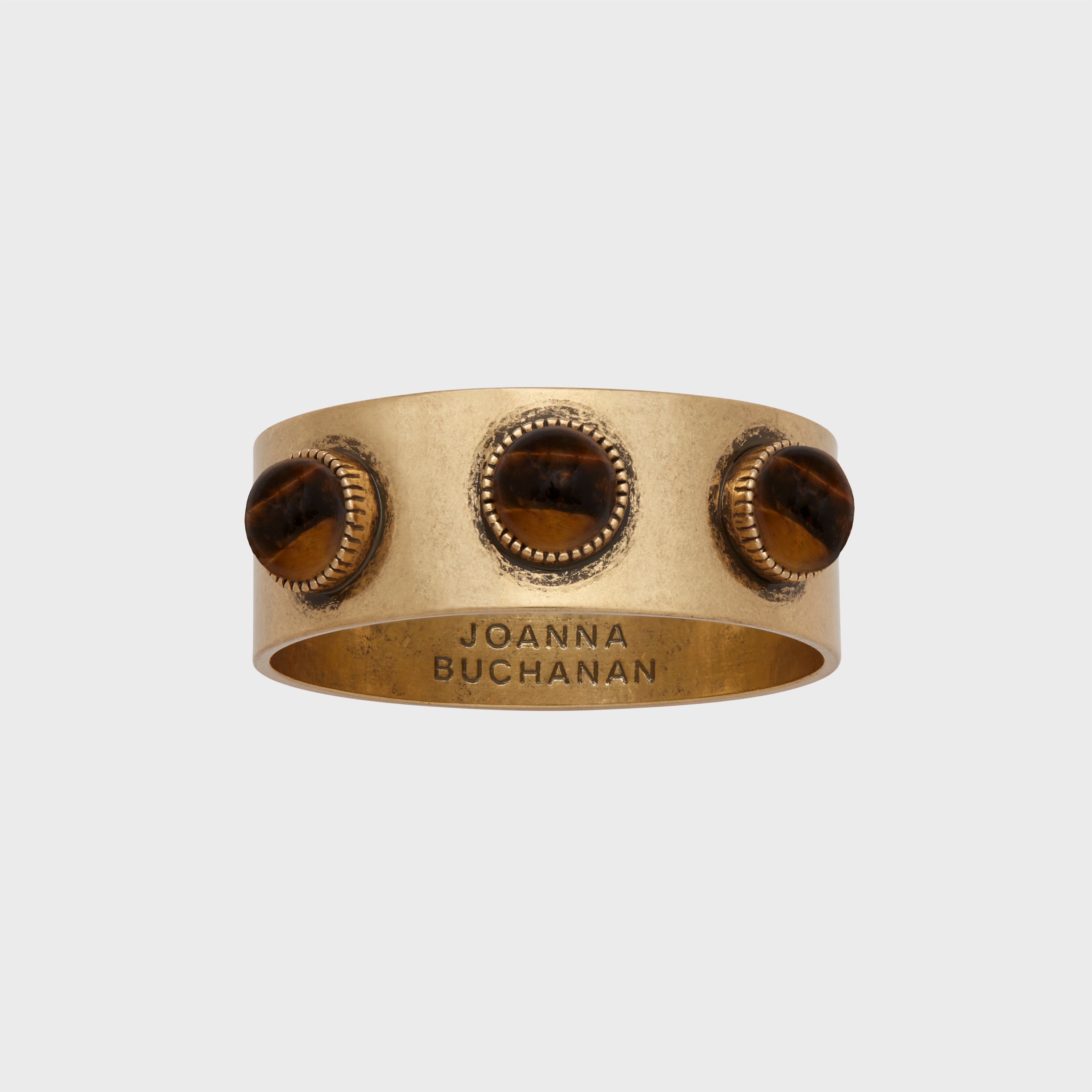 A set of brass napkin rings with a tiger's eye stone, featuring an antique gold finish.